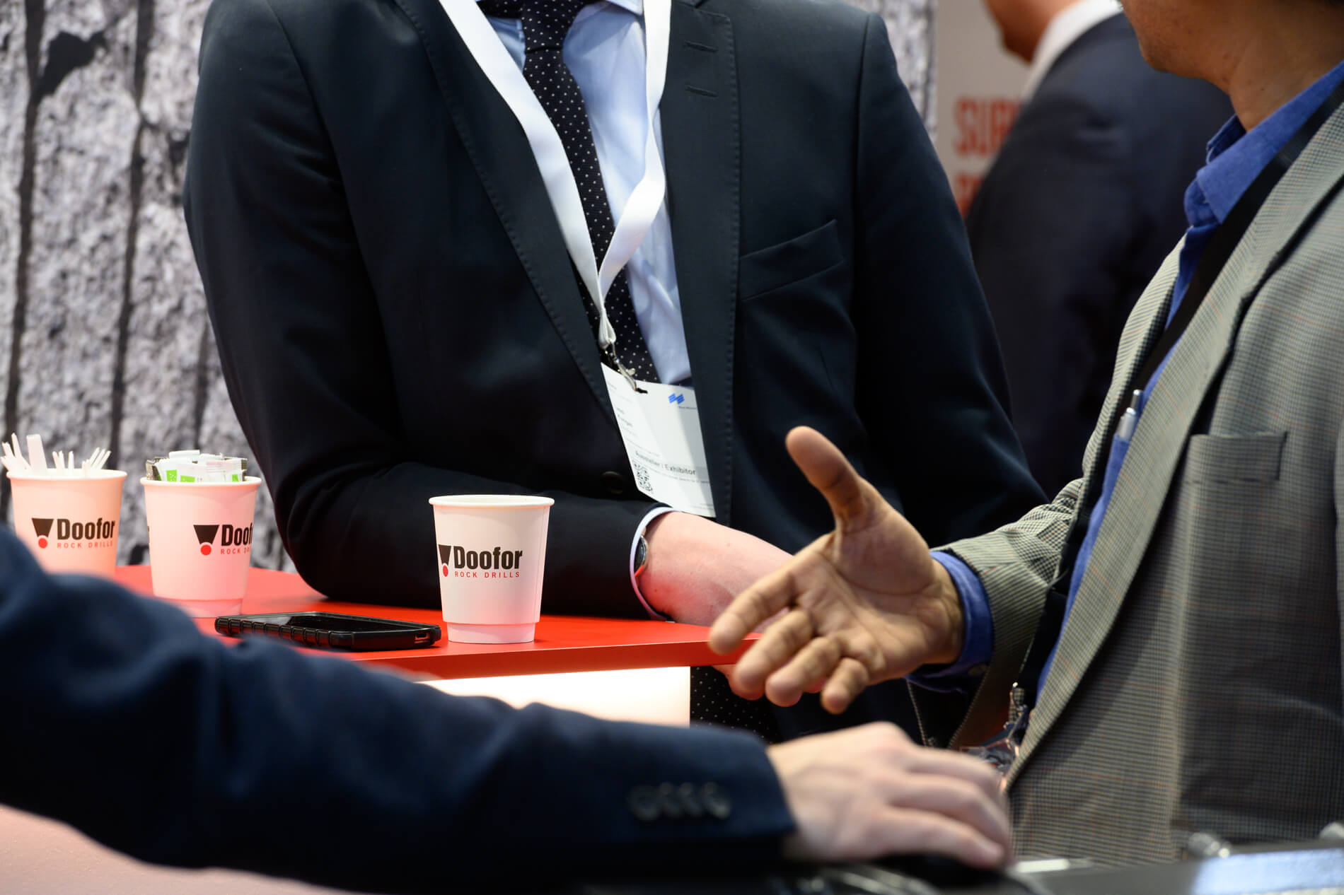 Professionals discussing drilling solutions around a standing table at Doofor’s B2B trade fair stand during an international industry event.